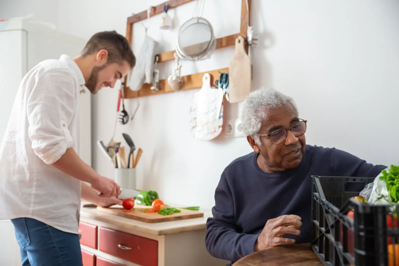 Zwei Männer bereiten in einer hellen Küche gemeinsam Gemüse vor.